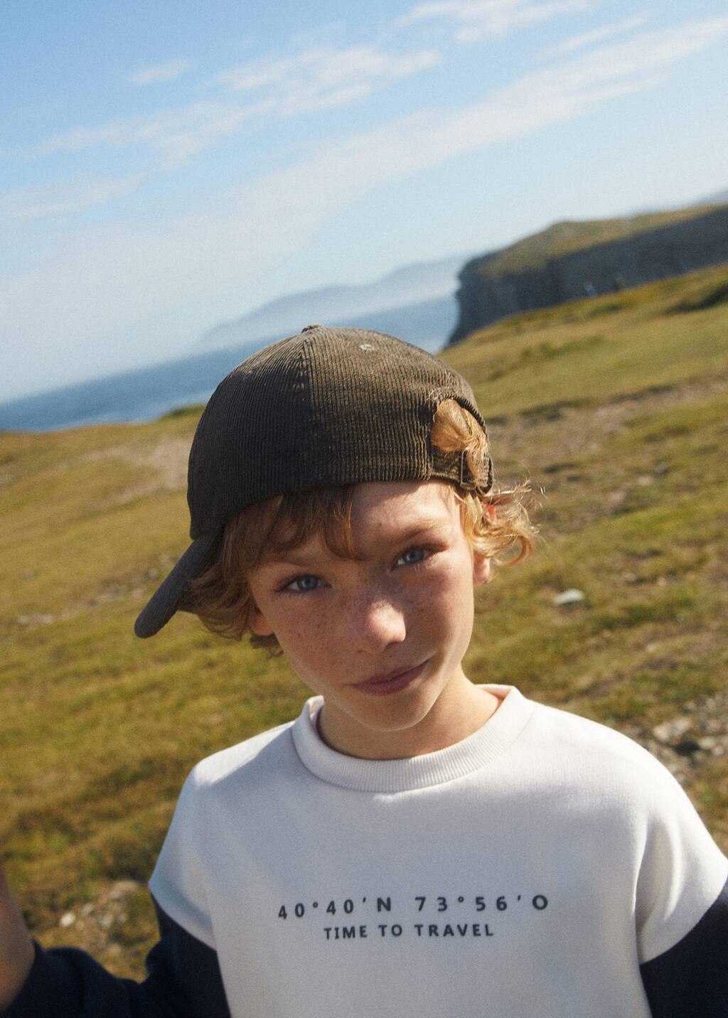 Mango Corduroy cap. a young boy wearing a hat standing in a field. 