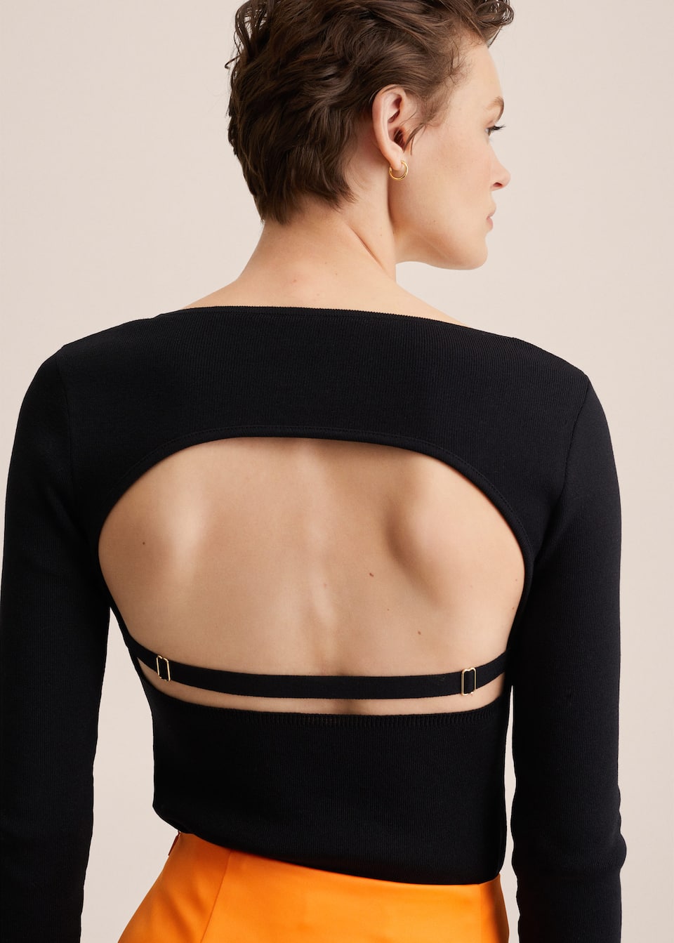 Black fine knit, cropped sweater with scoop neck, long sleeves ad open back detail, and back strap.
