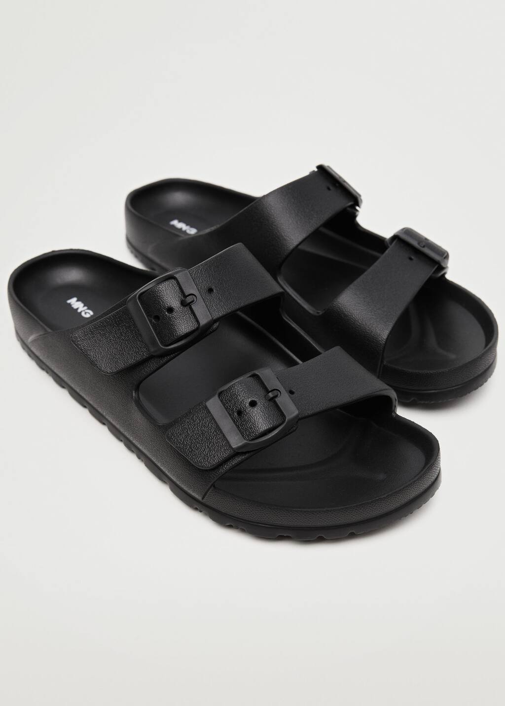 Mango Flip flops buckles. a pair of black sandals sitting on top of a white floor. 