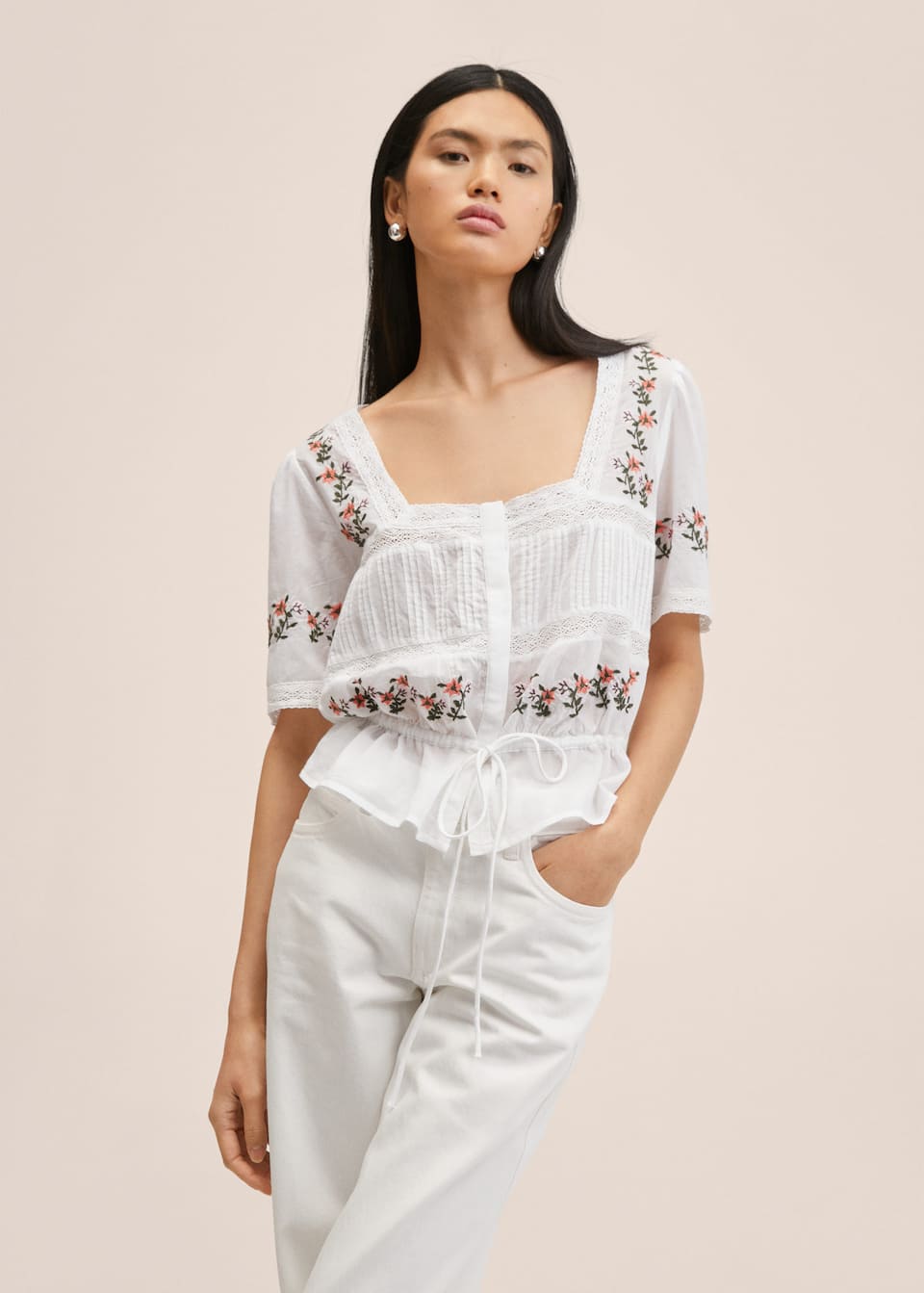 100% Cotton white blouse with floral embroidery. Square neck, short sleeves and Cropped design to the waist. Openwork details and trim. Concealed button closure on the front and drawstring tie waist.
