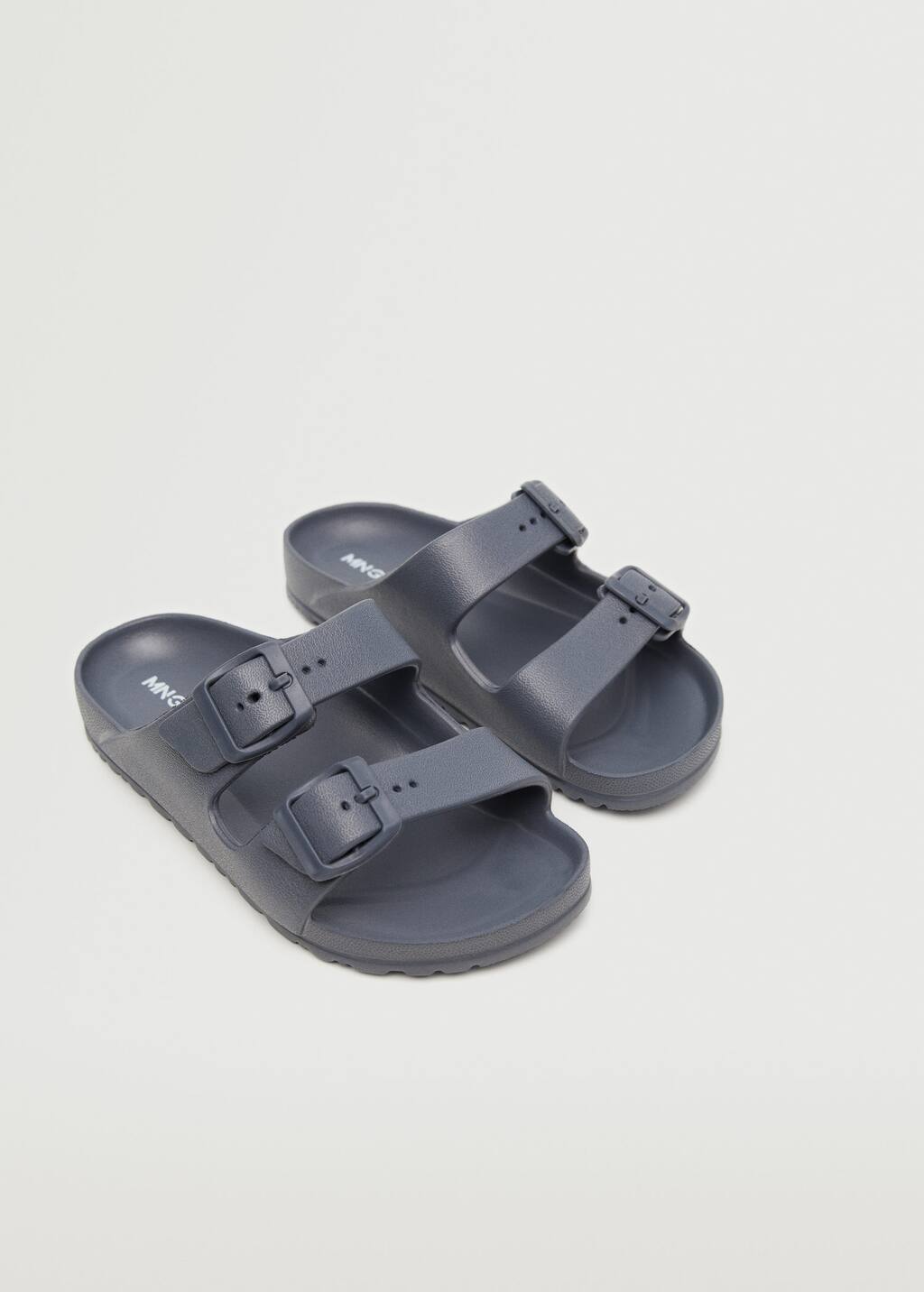 Mango Flip flops buckles. a pair of gray sandals on top of a white surface. 