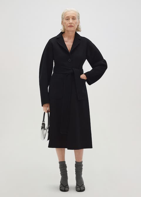 Mango selection collection black fitted handmade wool coat made from premium fabrics and tailored to a beautiful fit. Long, tailored design with a heavy structure. This coat has two side patch pockets, a single-breasted button fastening, and a detachable self-tie belt. Committed Collection.