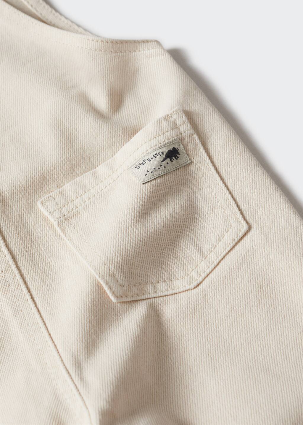 Mango Long denim jumpsuit. a close-up view of a pocket on a white shirt. 