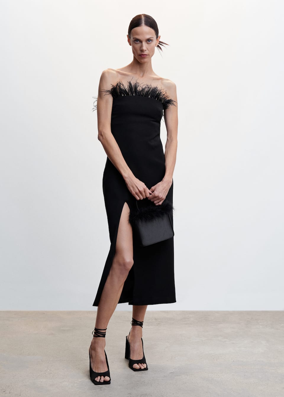 Mango black bandeau neckline midi dress with feathered trim on the neckline. this midi dress has a Tailored design with a side slit and a Detachable feather trim. Invisible back zip fastening. Inner lining. Party and events collection.