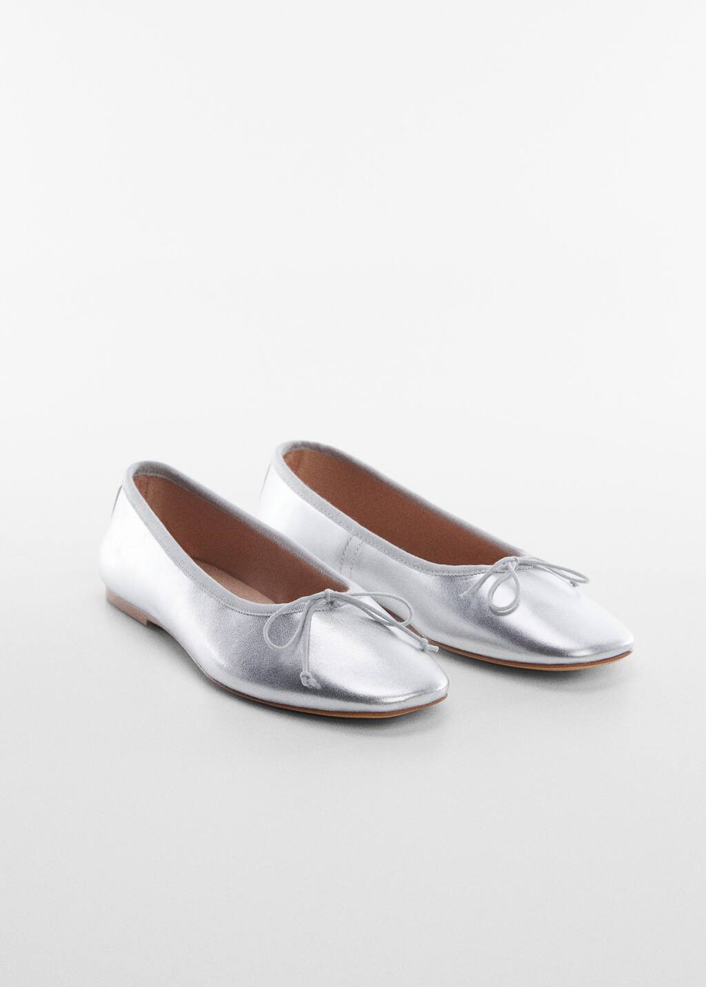 Mango Bow leather ballerina. a pair of silver shoes on a white surface. 