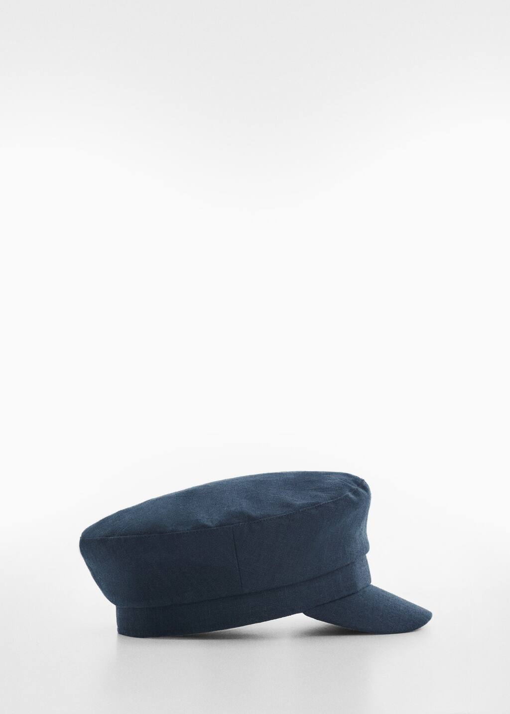 Mango Cap with visor. a black hat is sitting on top of a table. 