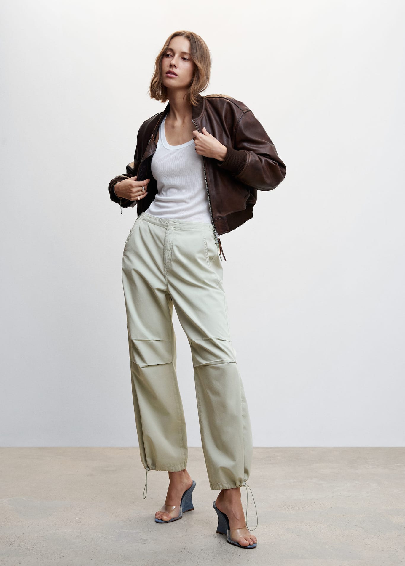 Mango beige parachute pants in 100% cotton fabric. These flowy cargo parachute pants have a medium Adjustable waist with inner elastic and a Concealed zip and button fastening. These pants have Two side pockets and Two patch pockets on the back. The Hem has an adjustable elastic feature too.