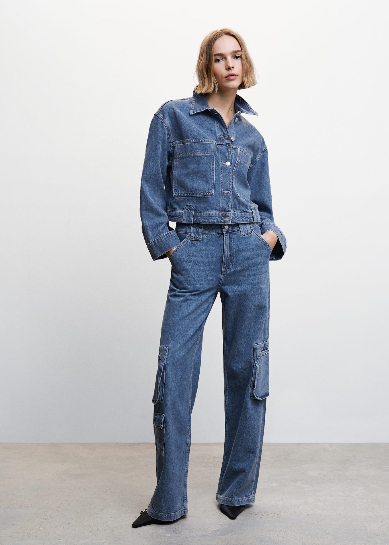 Mango Circular Design Collection. Denim style cotton fabric. Recycled cotton-blend fabric jeans in a mid blue wash with a Cargo design. They have a Medium waist and Two cargo pockets, Two side pockets, Zip and one button fastening.