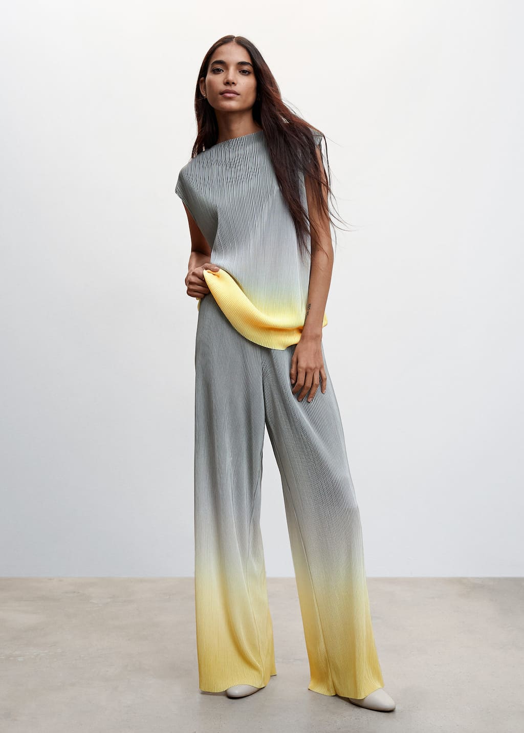 Mango Pleated palazzo trousers. a woman standing in front of a white wall. 