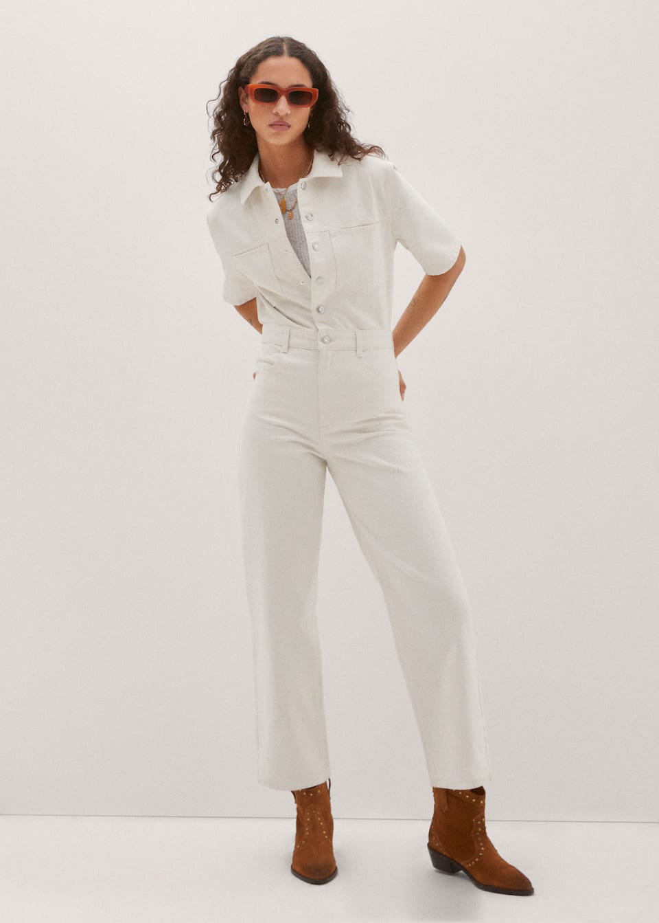 Mango ecru short-sleeved denim jumpsuit with shirt collar, and silver buttons up the front. two patch pockets on the chest and back pockets. Cinched waist with belt loops.