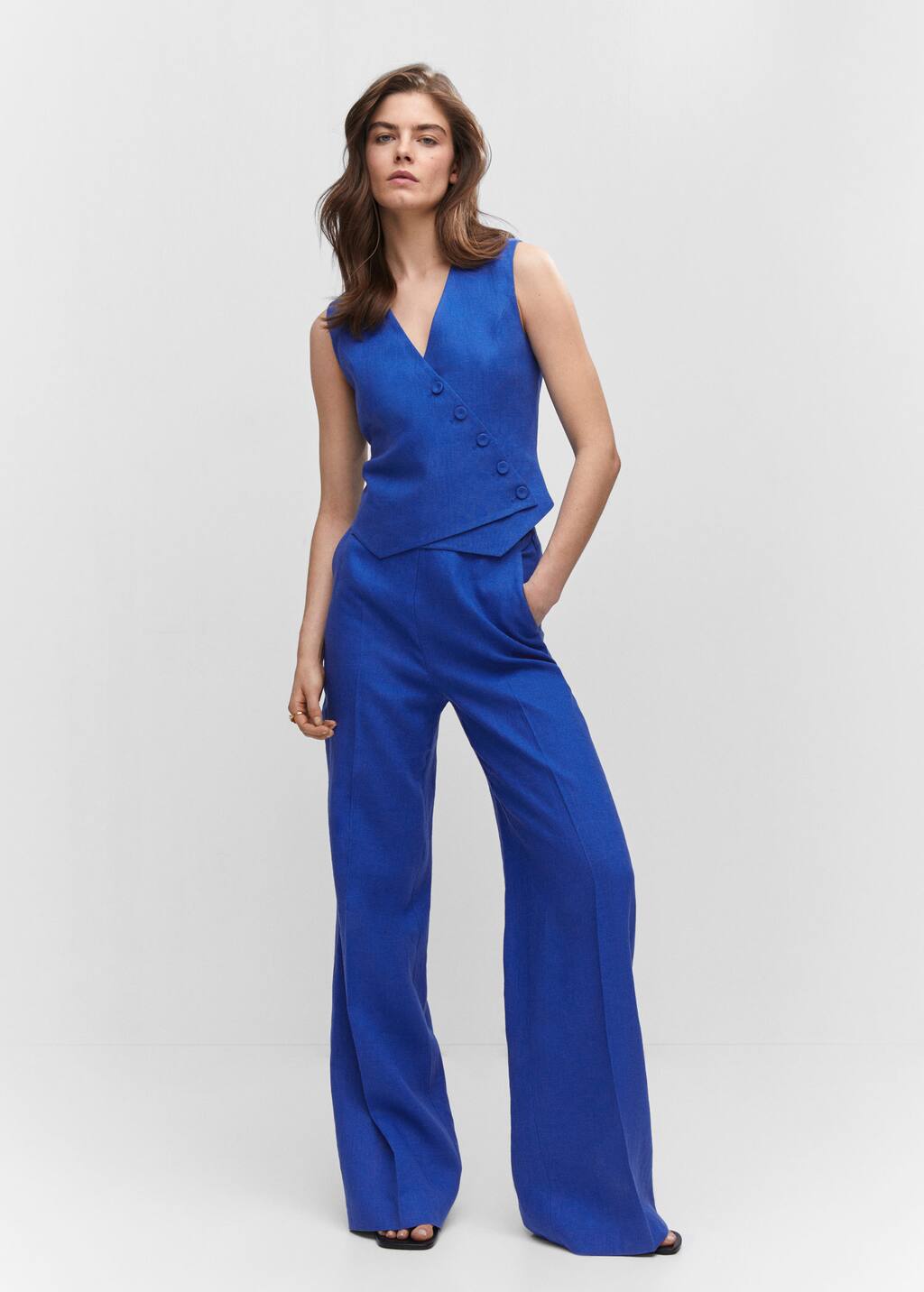 Mango Double-breasted linen vest. a woman in a blue suit standing in front of a white wall. Mango Double-breasted linen vest. a woman in a blue suit standing in front of a white wall.