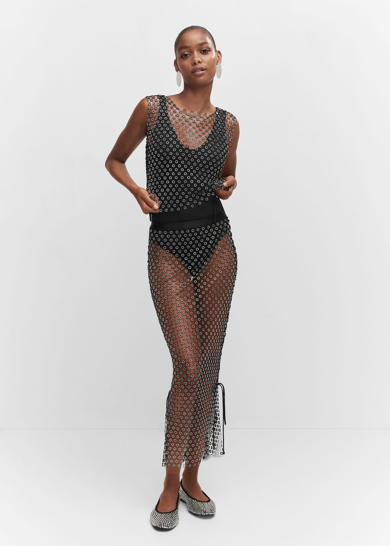 Spice up your summer party looks Mango's sheer crystal embellished sleeveless top with round neck and lace up sides, worn with the matching sheer skirt.